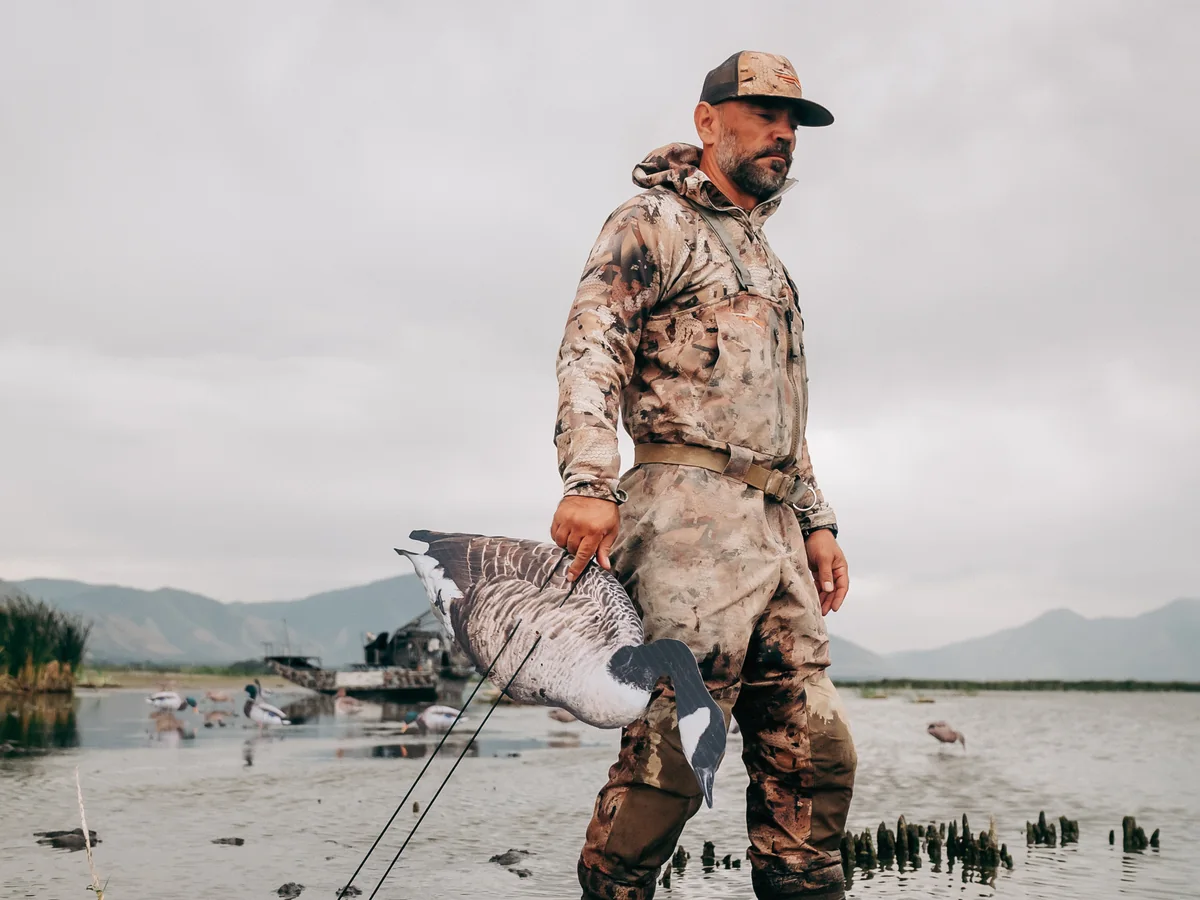 A hunter wading out to set a spread of Committed Waterfowl decoys